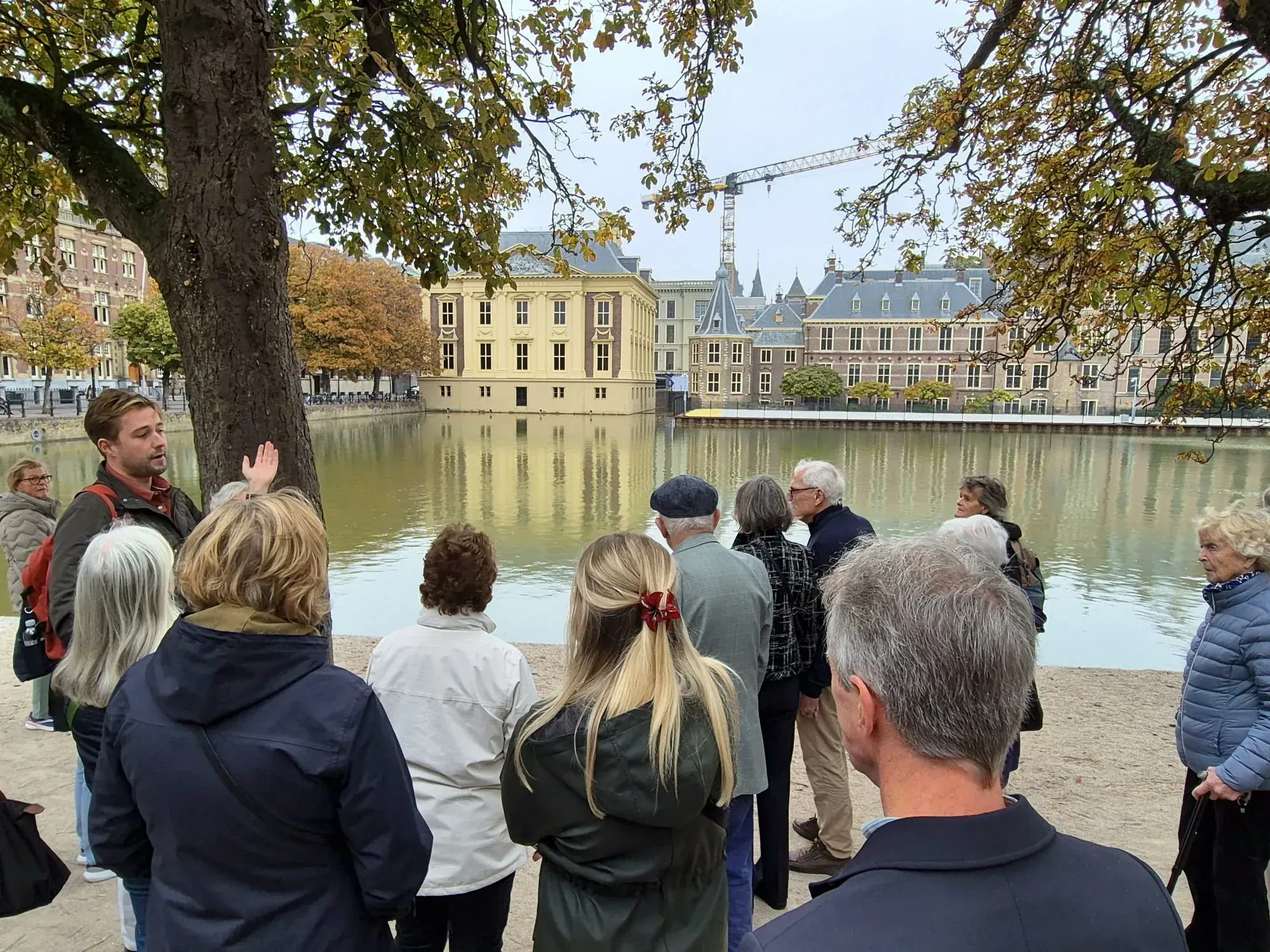 Ein Guide und eine Gruppe blicken über den Hofvijver zum Mauritshuis, bei einer privaten Stadtführung durch Den Haag