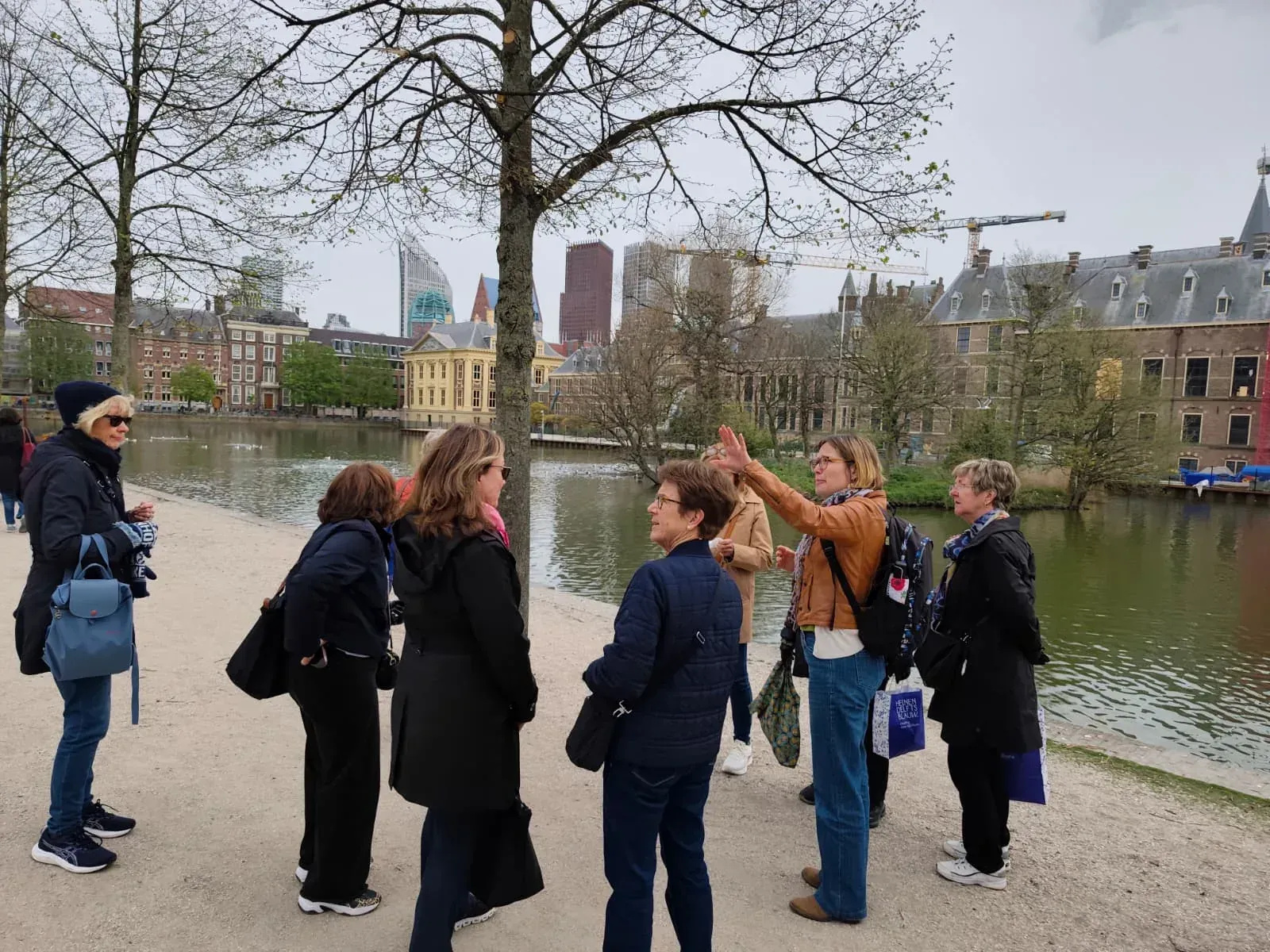 A guide with a group at the Hofvijver, with the Binnenhof behind