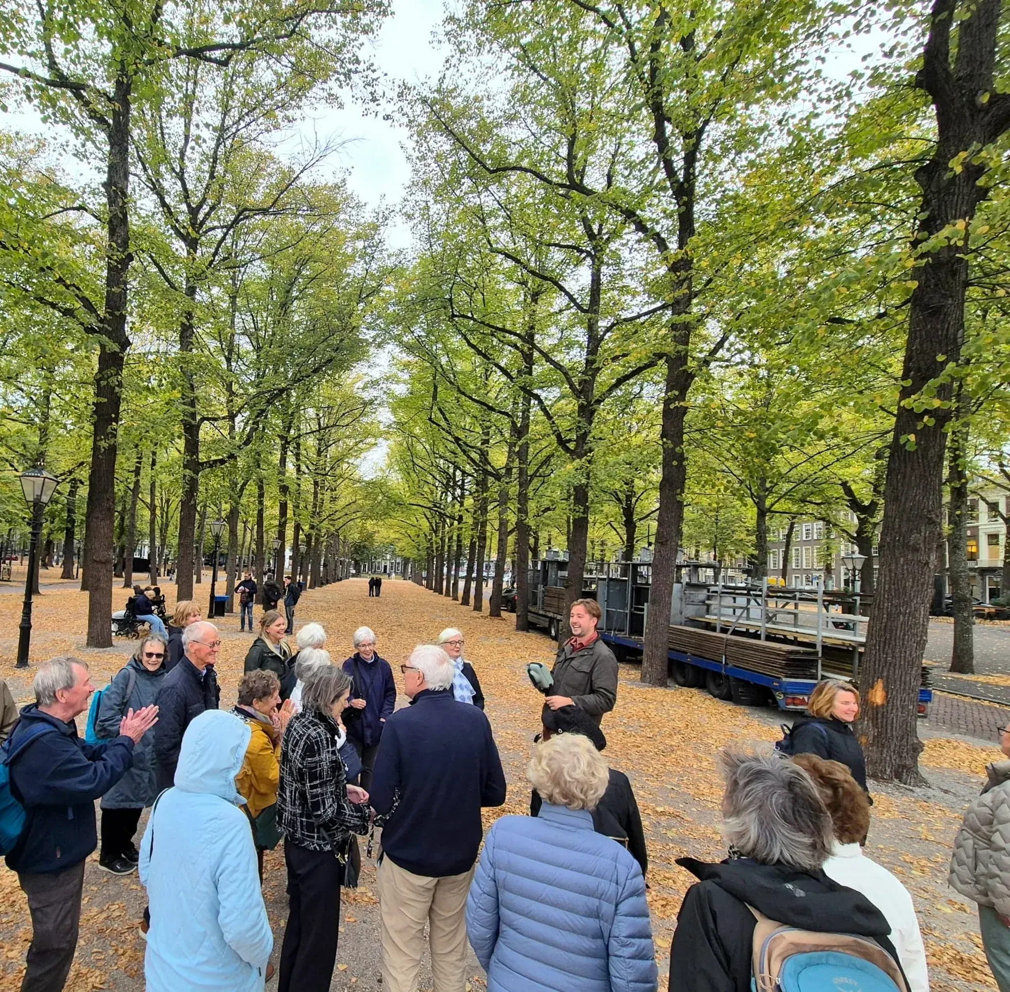 A guide and tour group on the tree-lined Lange Voorhout during a guided walking dinner in The Hague