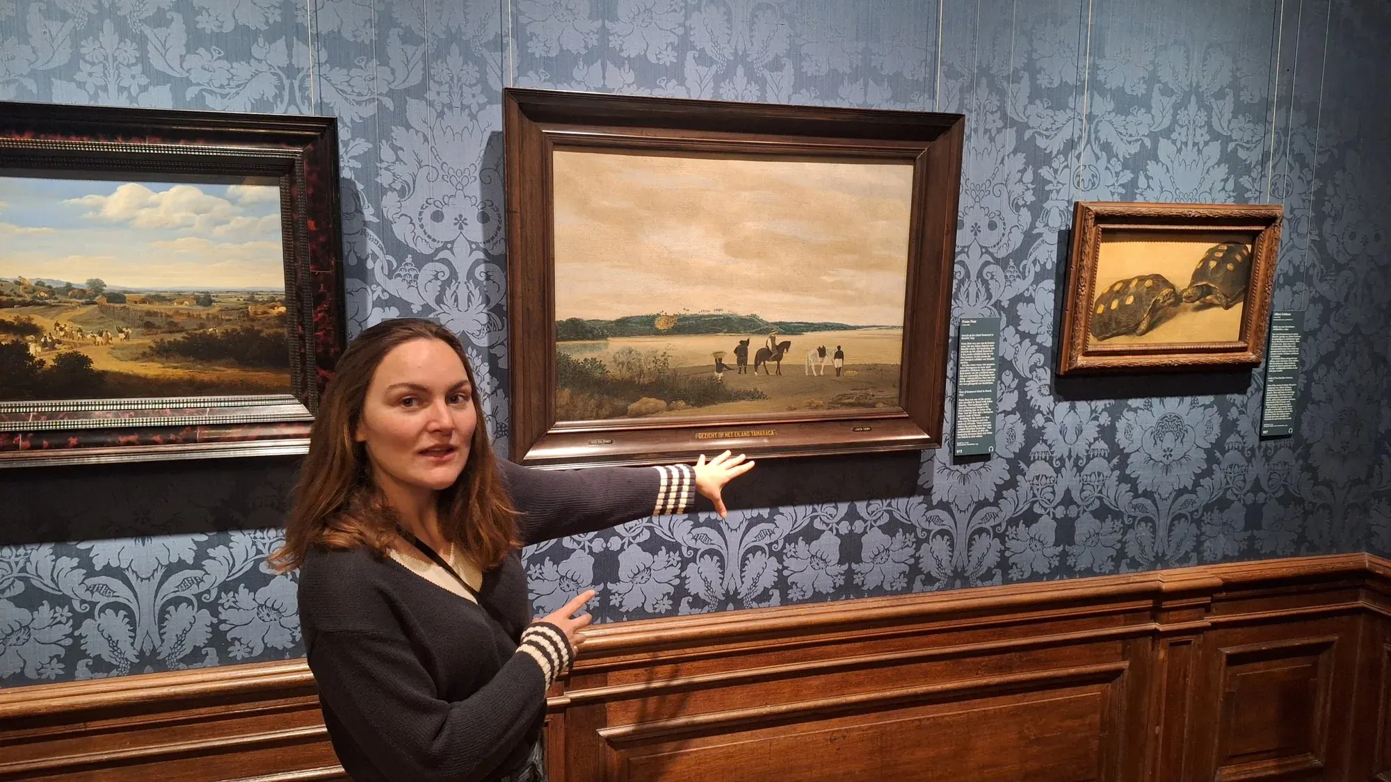 Een gids vertelt over het Braziliaanse landschap van Frans Post, naast een schilderij van schildpadden, Mauritshuis