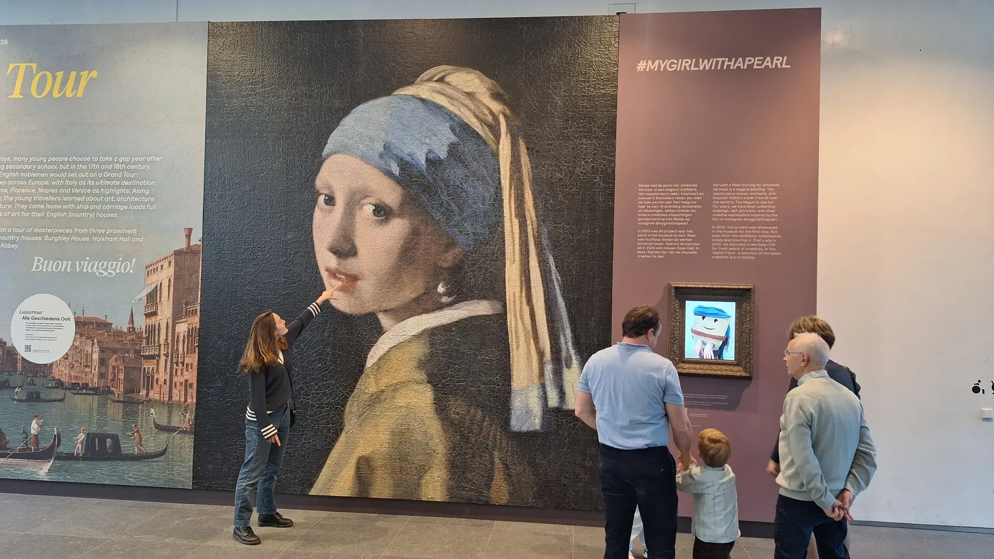 Een gids naast het muurgrote Meisje met de parel in de entreehal van het Mauritshuis in Den Haag