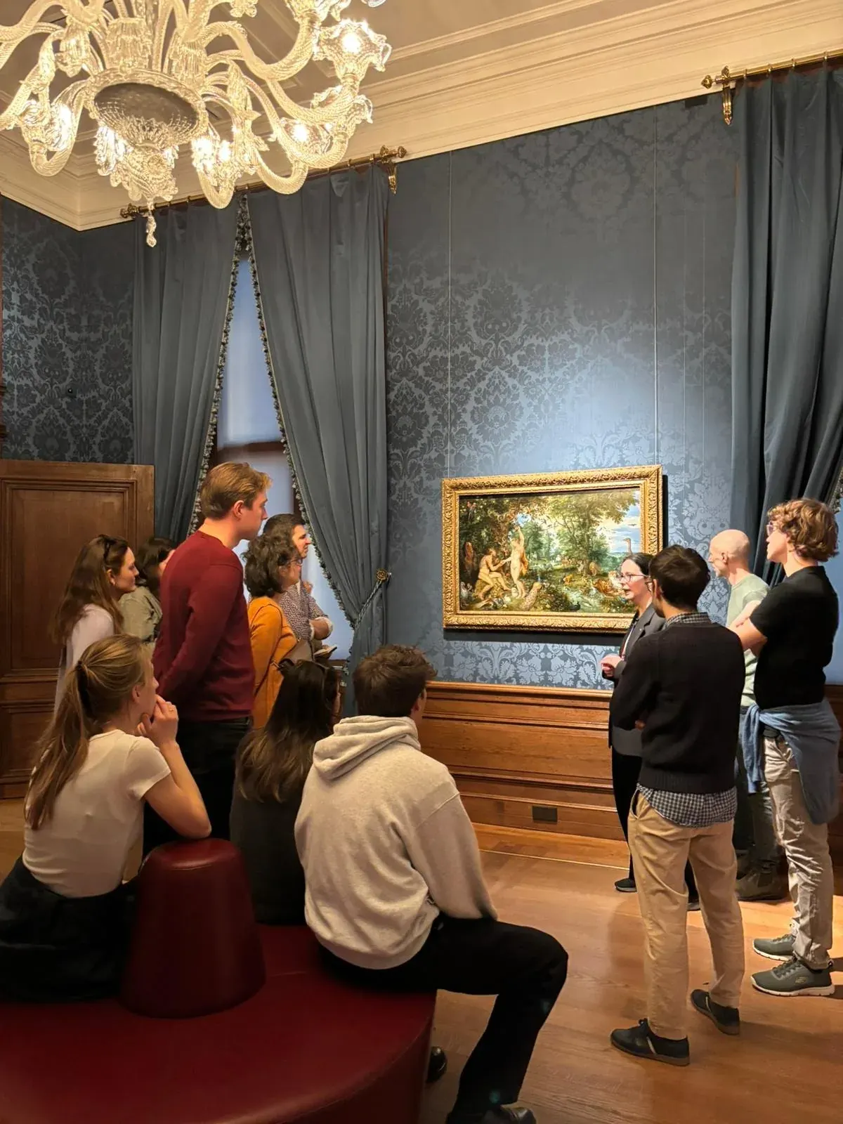Een gids en groep voor het grote schilderij van de Hof van Eden in het Mauritshuis in Den Haag