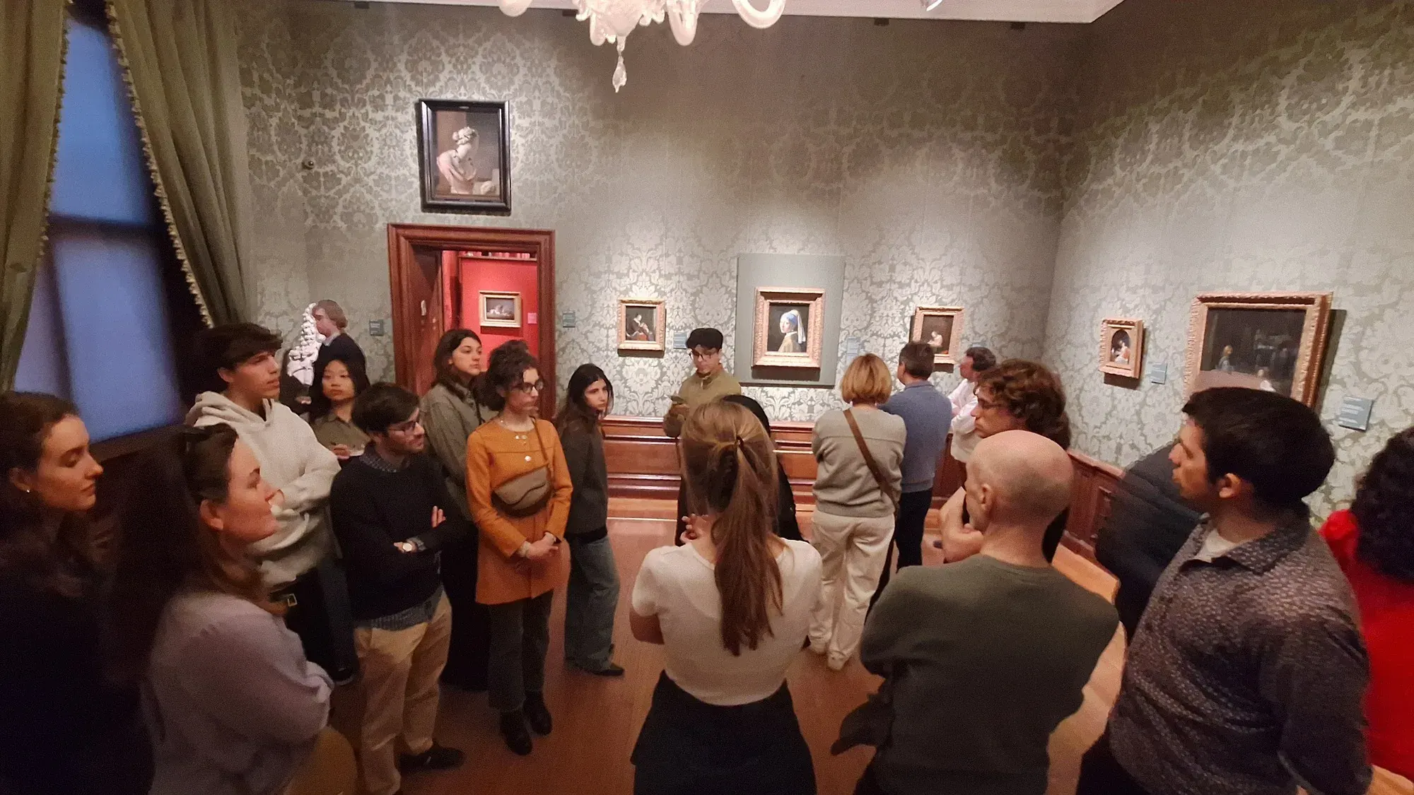 Een groep met hun gids in de zaal van het Mauritshuis waar het Meisje met de parel hangt